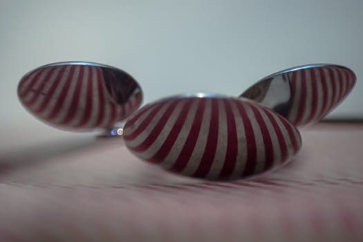 Three spoons composed to reflect red vertical lines