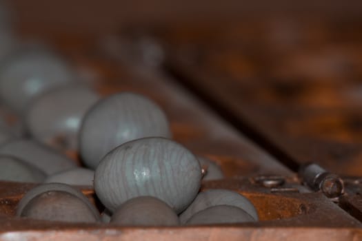 Closeup of a wooden mancala game with grey stones