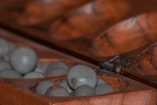 Closeup of a wooden mancala game with grey stones