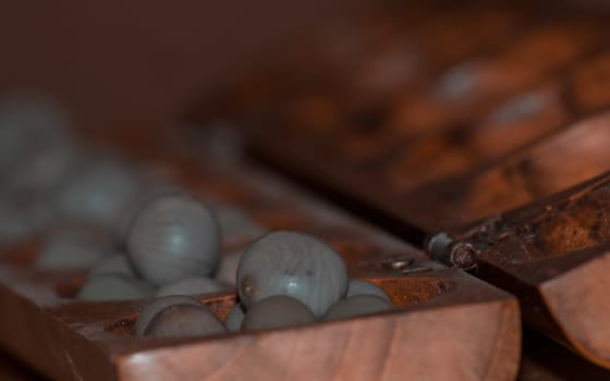 Closeup of a wooden mancala game with grey stones