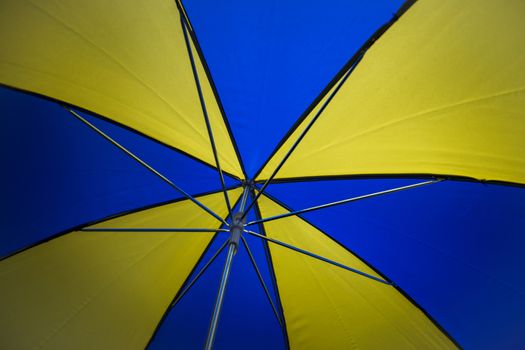 Underneath a blue and yellow umbrella