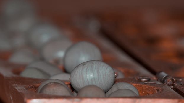 Closeup of a wooden mancala game with grey stones