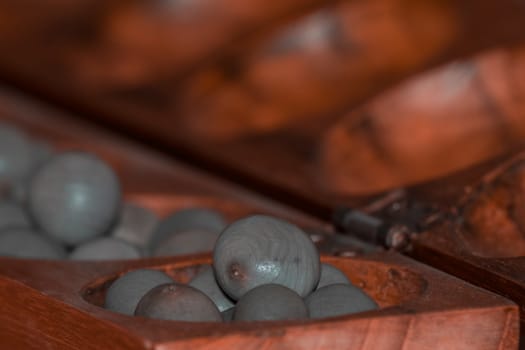 Closeup of a wooden mancala game with grey stones