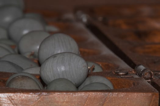 Closeup of a wooden mancala game with grey stones