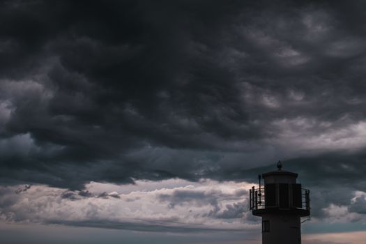 The silhouette of a lighthuse infront of a stormy cloudscape