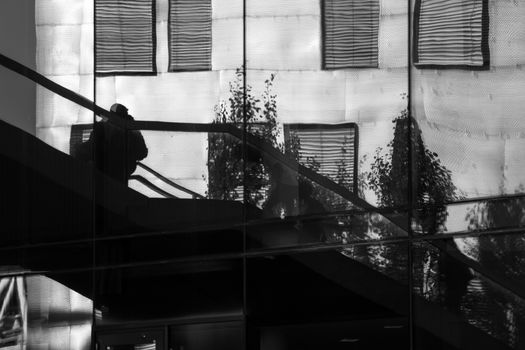 Reflection of people walking up and down some stairs in the city