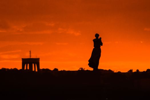Silhouette of a woman and an arch during an orange sunset