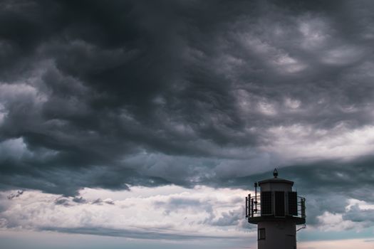 The silhouette of a lighthuse infront of a stormy cloudscape