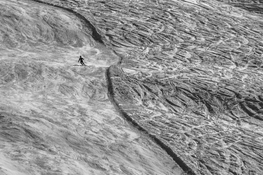 A skiier skiing downhill an alpine slope