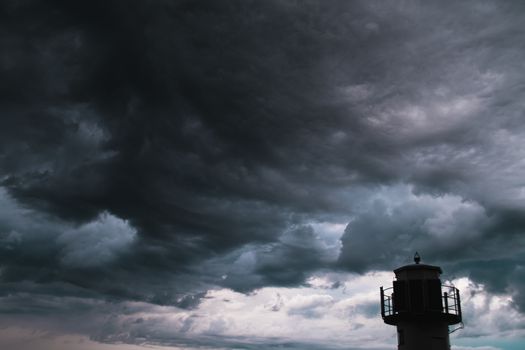 The silhouette of a lighthuse infront of a stormy cloudscape