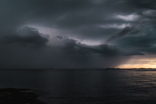 Stormy powerful clouds by the ocean during sunset