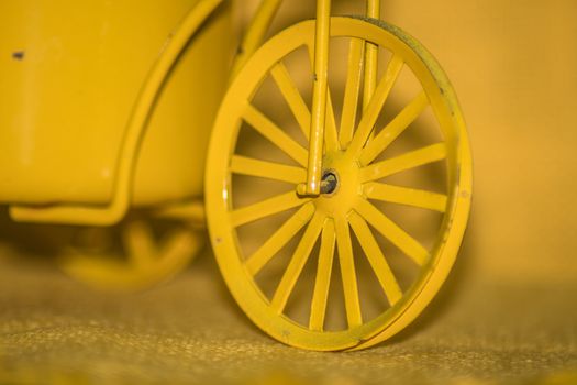 Closeup of a yellow toy wheel infront of a yellow background