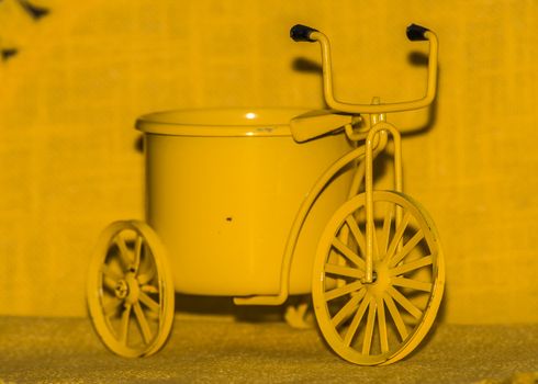 A yellow toy bike with a yellow background
