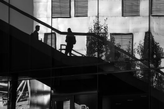 Reflection of people walking up and down some stairs in the city