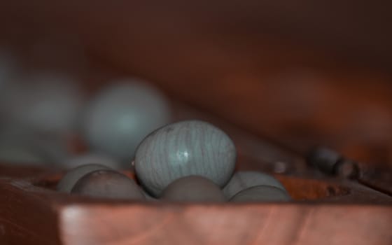 Closeup of a wooden mancala game with grey stones