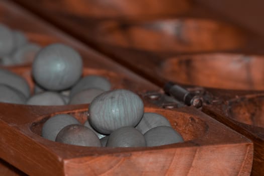 Closeup of a wooden mancala game with grey stones