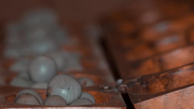 Closeup of a wooden mancala game with grey stones