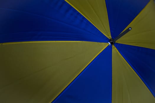 Ontop of a blue and yellow umbrella