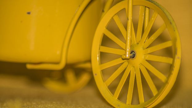 Closeup of a yellow toy wheel infront of a yellow background