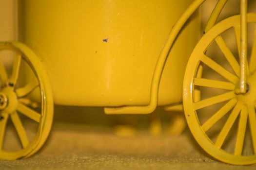 Closeup of a yellow toy wheel infront of a yellow background