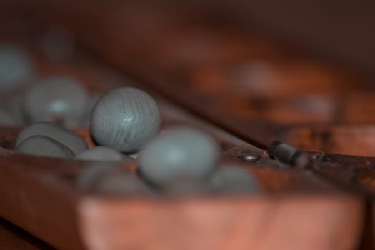 Closeup of a wooden mancala game with grey stones