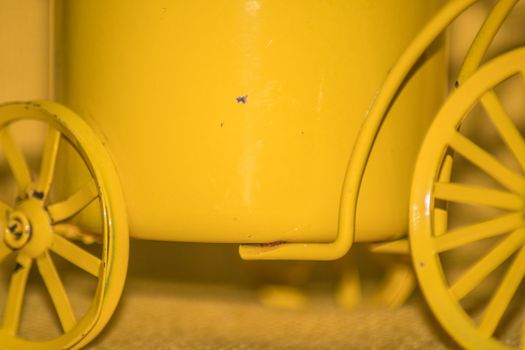 Closeup of a yellow toy wheel infront of a yellow background