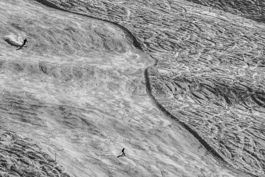 Two skiiers skiing downhill an alpine slope