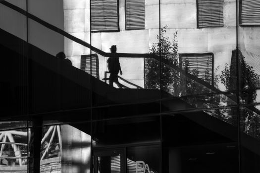 Reflection of people walking up and down some stairs in the city