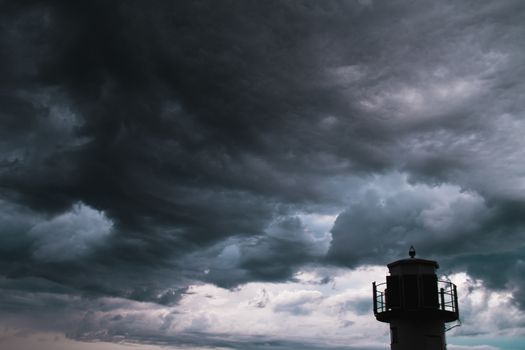 The silhouette of a lighthuse infront of a stormy cloudscape