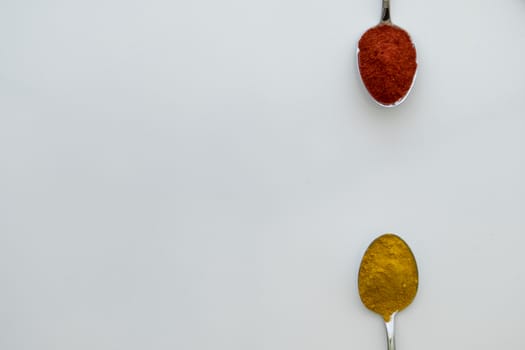 Various colorful spices arranged on spoons  with a white background