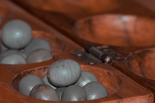 Closeup of a wooden mancala game with grey stones