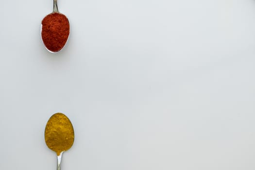 Various colorful spices arranged on spoons  with a white background