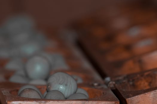 Closeup of a wooden mancala game with grey stones