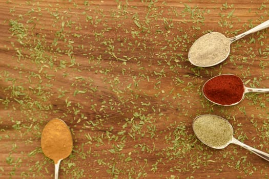 Various colorful spices arranged on spoons  with wooden background