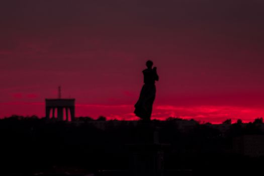 Silhouette of a woman and an arch during a pink sunset