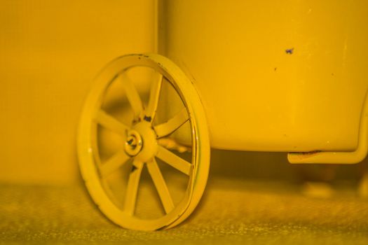 Closeup of a yellow toy wheel infront of a yellow background