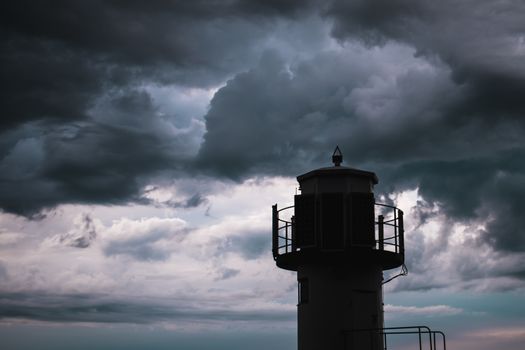 The silhouette of a lighthuse infront of a stormy cloudscape