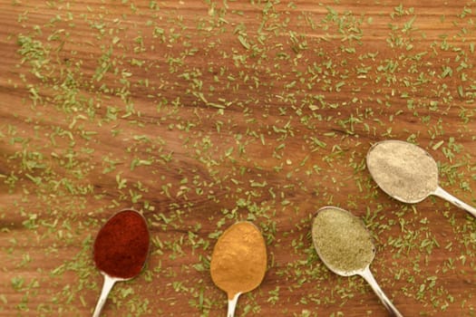 Various colorful spices arranged on spoons  with wooden background