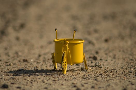 A yellow toy tricycle on a gravel road