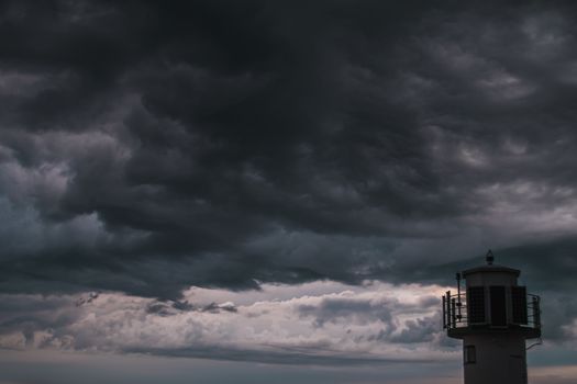 The silhouette of a lighthuse infront of a stormy cloudscape