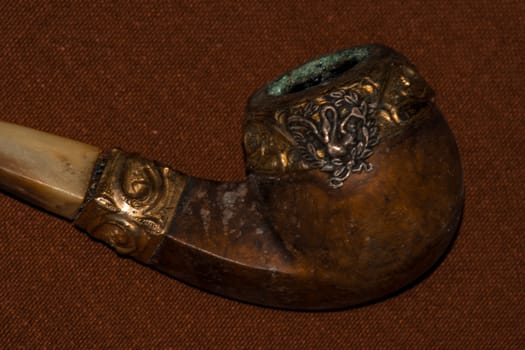 Still life of an old retro wooden tobacco pipe on a brown background