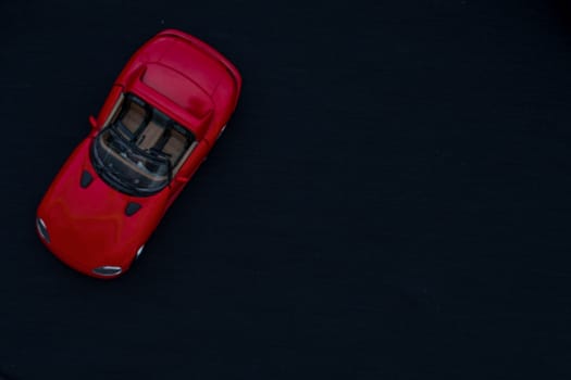 Flat lay of a red toy car with black background