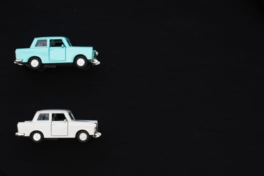 Flat lay of a white and blue toy car with a black background