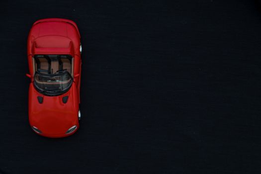 Flat lay of a red toy car with black background