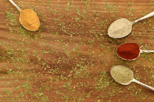 Various colorful spices arranged on spoons  with wooden background