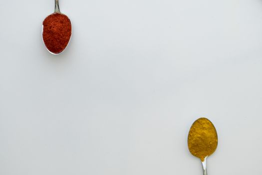 Various colorful spices arranged on spoons  with a white background