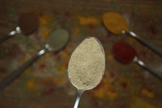 Closeup of white pepper on a spoon with other spices in the background