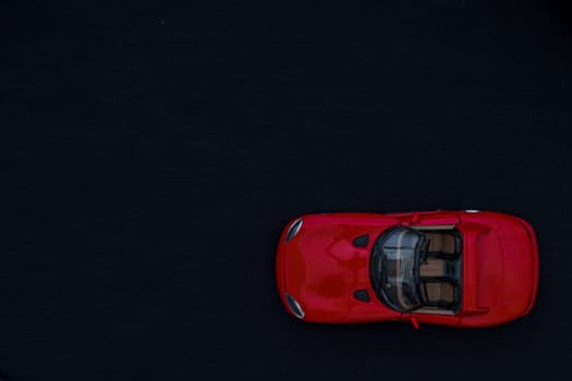 Flat lay of a red toy car with black background