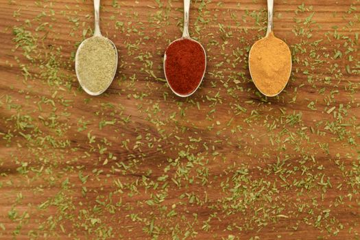 Various colorful spices arranged on spoons  with wooden background