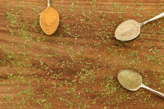 Various colorful spices arranged on spoons  with wooden background